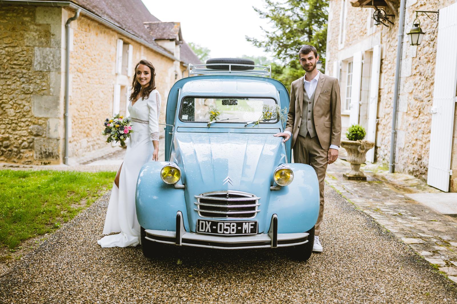 Portrait des mariés devant une 2CV bleue, mariage en Périgord
