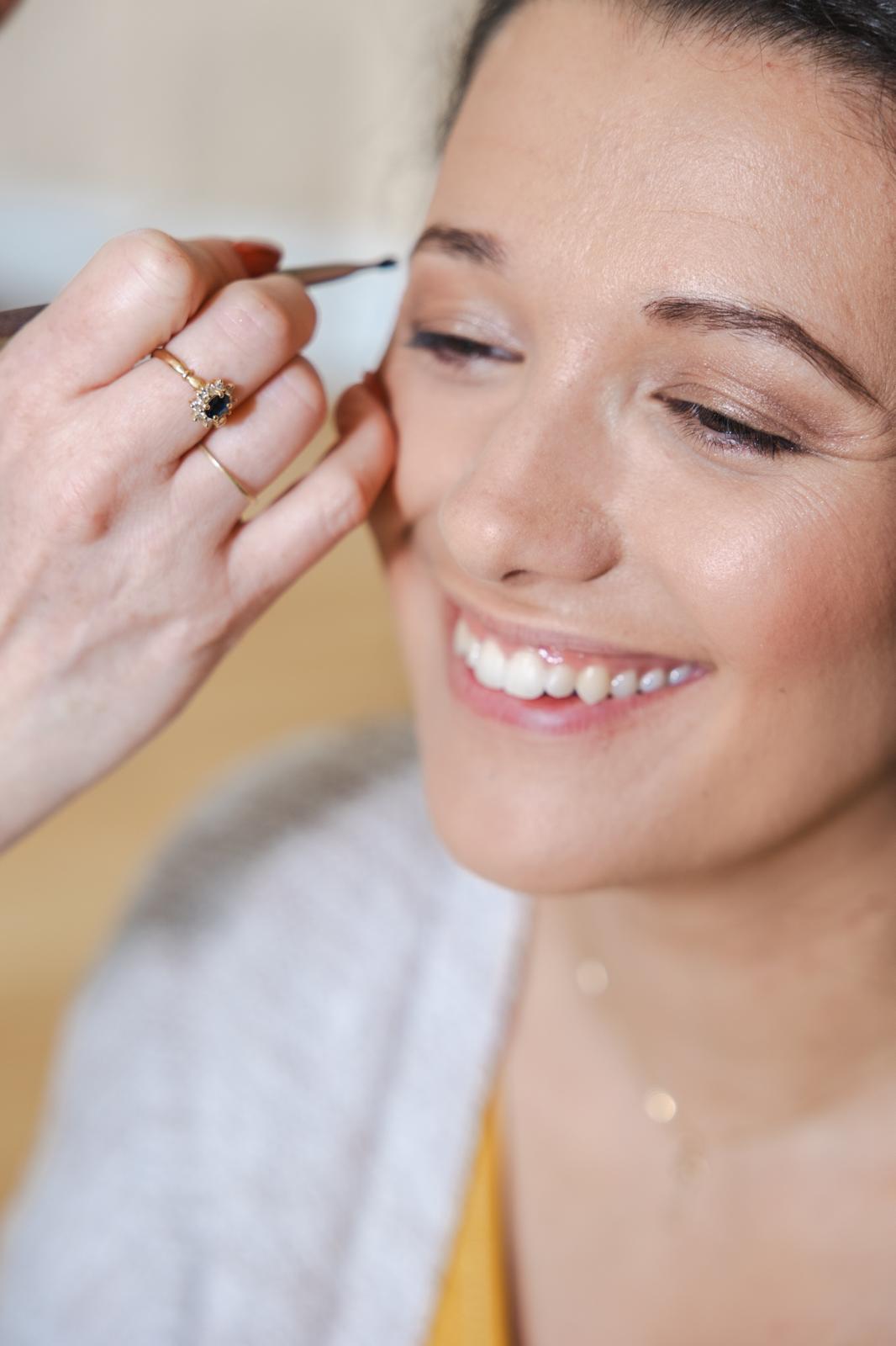 Maquillage nude lumineux appliqué au pinceau sur une mariée souriante