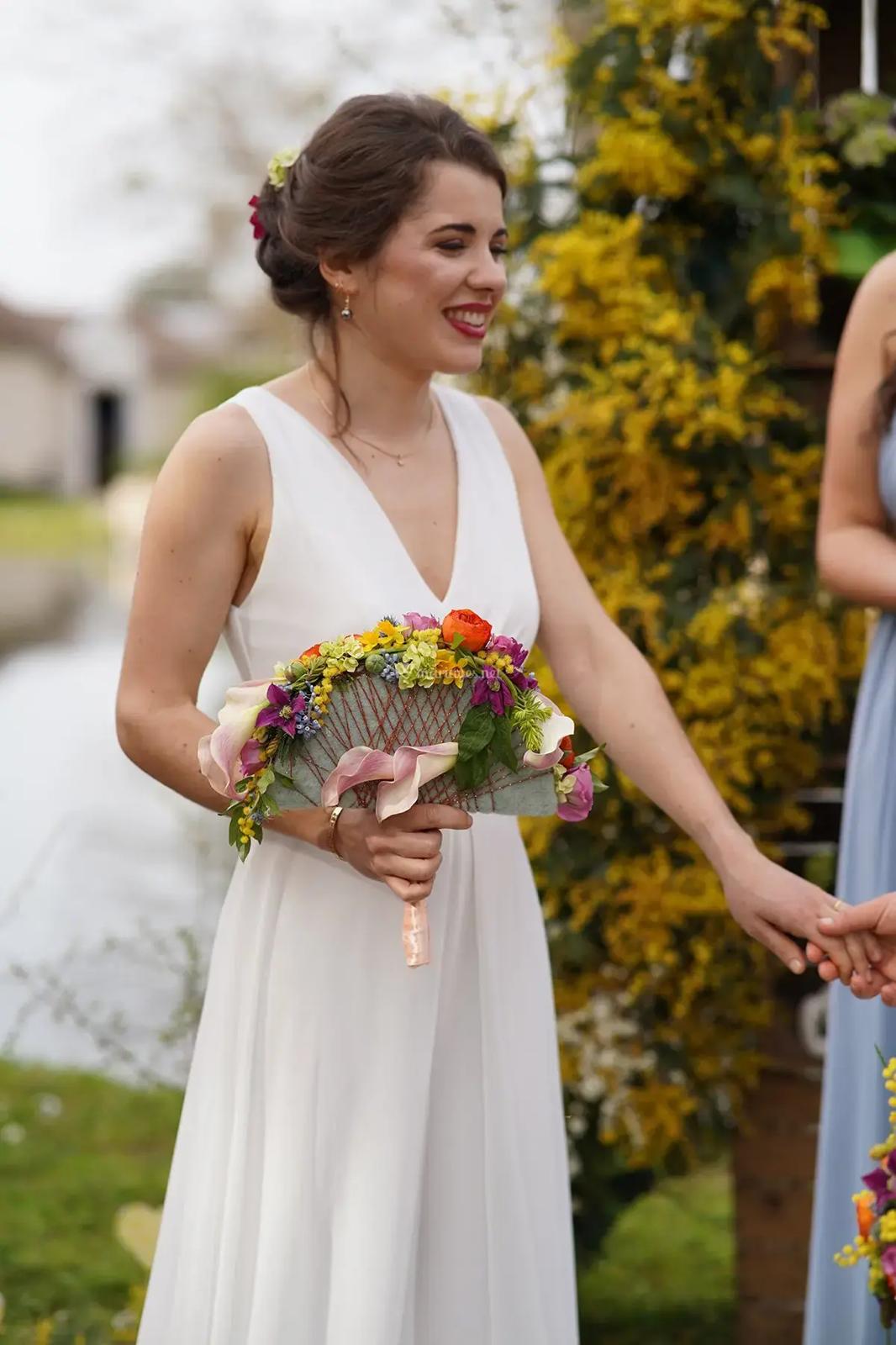 Mariée souriante coiffée d'un chignon fleuri lors de sa cérémonie