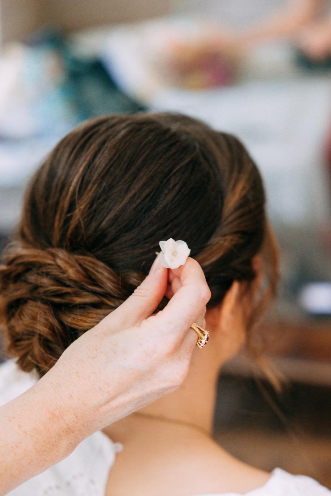 Pose d'une fleur blanche dans un chignon bas de mariée