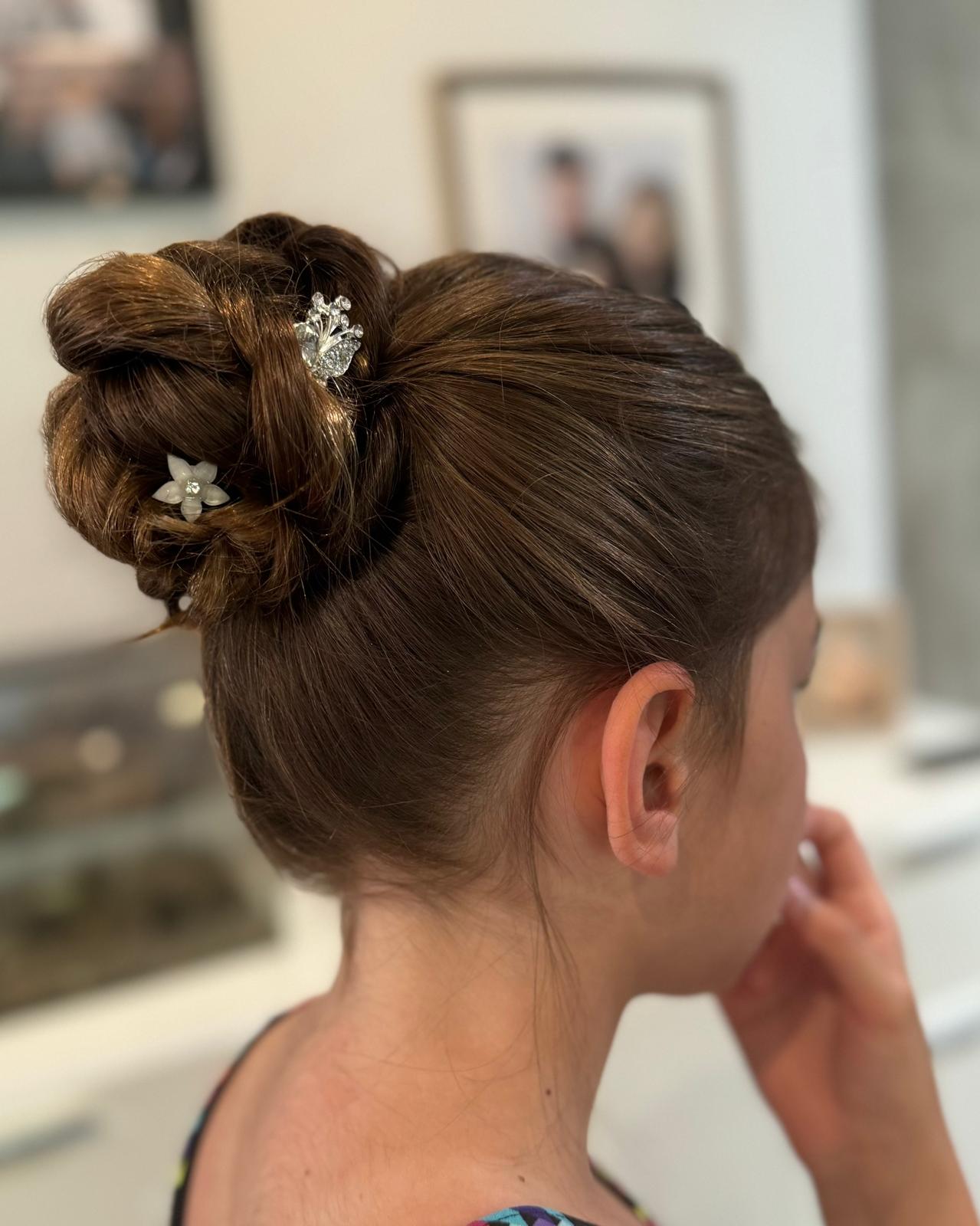 Chignon haut travaillé d'enfant d'honneur avec bijoux fleuris, mariage en Dordogne