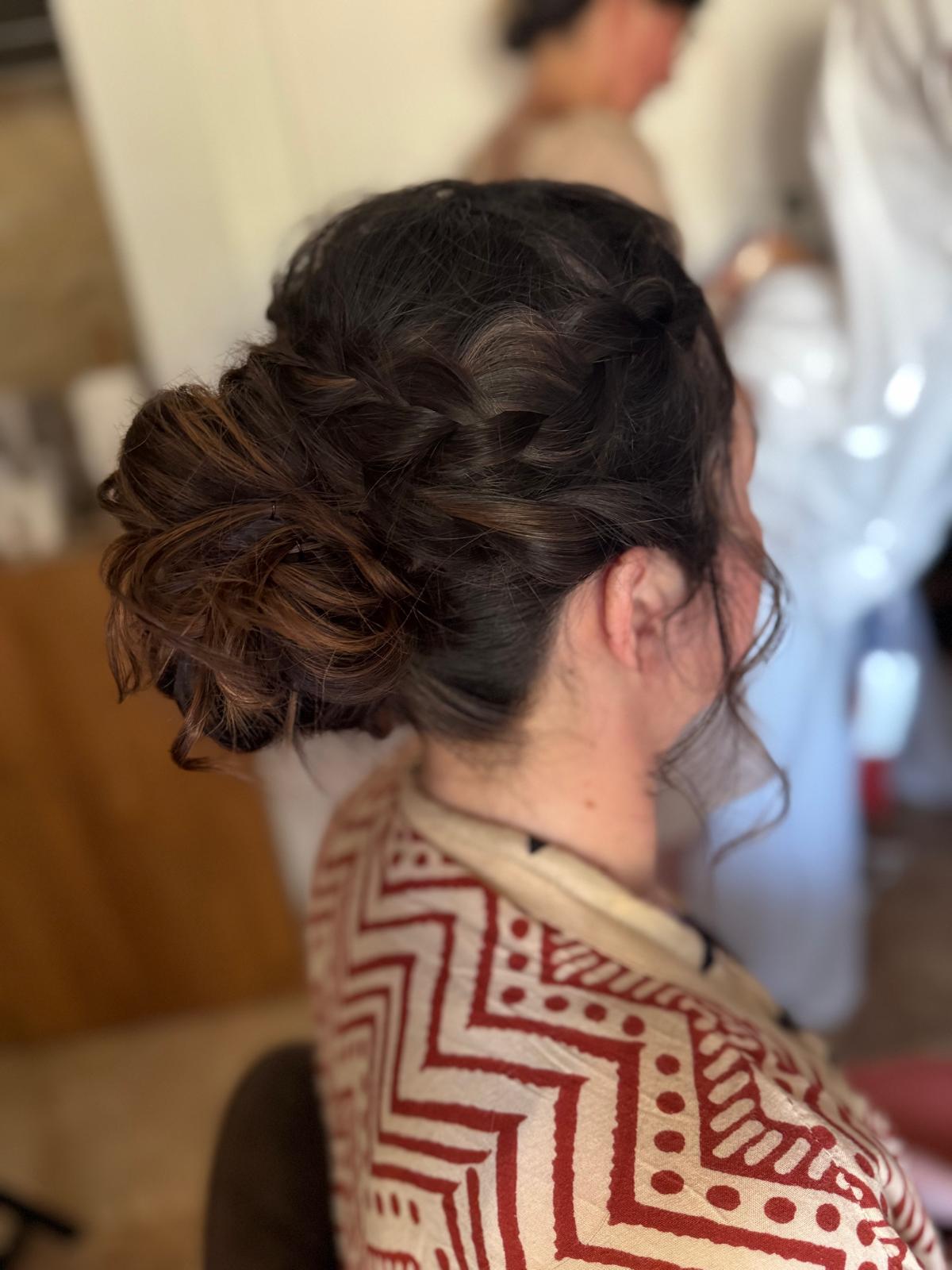 Chignon flou tressé sur cheveux bruns, mise en beauté d'invitée de mariage